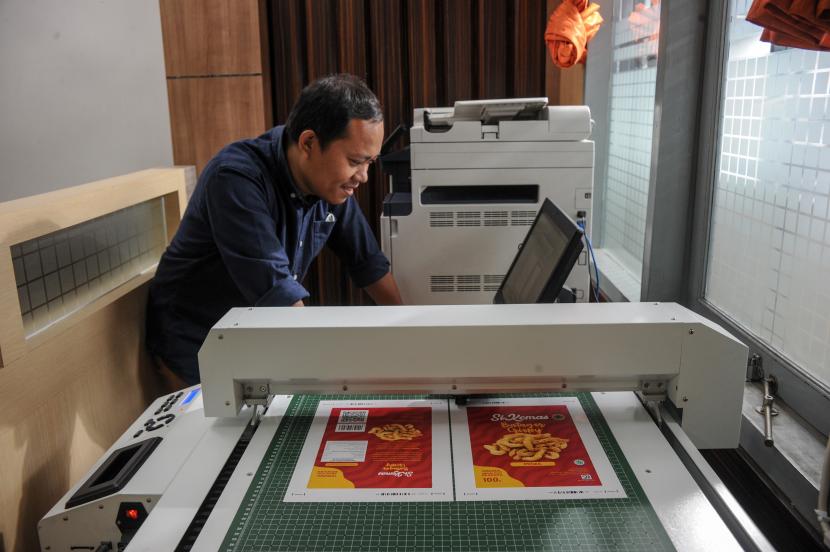 Seorang pekerja mencetak desain kemasan produk kuliner UMKM.
