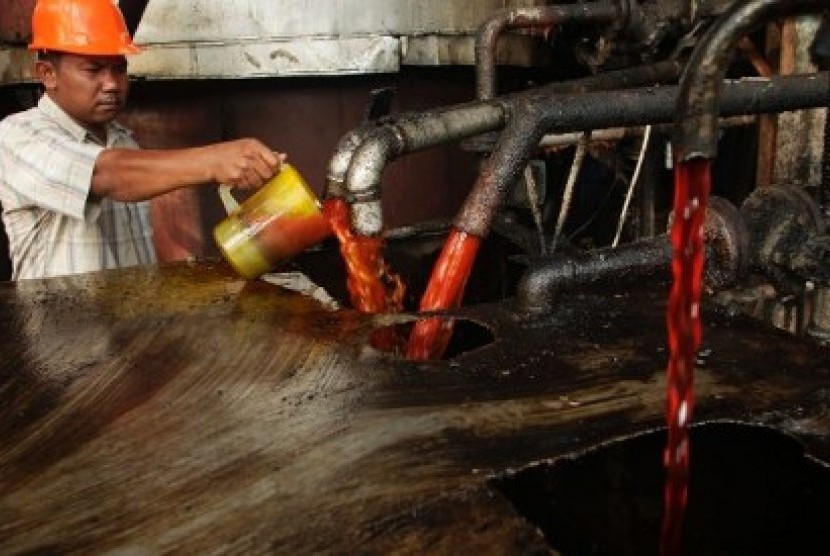 Seorang pekerja mengecek kualitas minyak sawit mentah (CPO) di pabrik pembuatan minyak sawit.