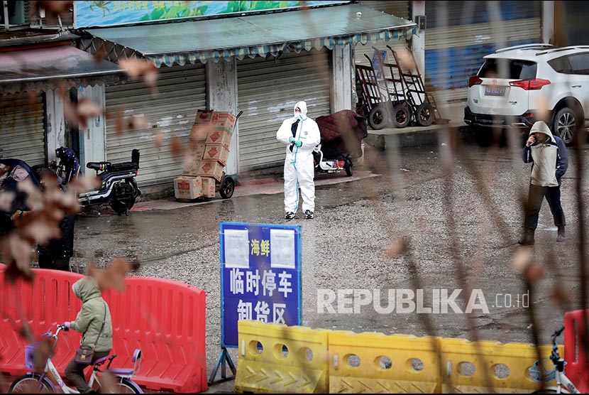 Seorang pekerja mengenakan pakaian Hazmat  di pasar ikan yang ditutup di Wuhan, Provinsi Hubei, China, Kamis (23/1).