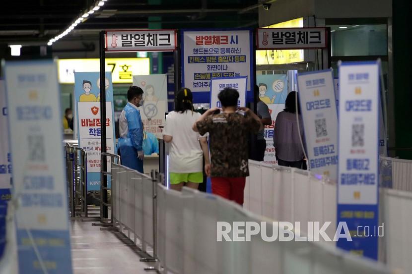 Seorang pekerja mengenakan pelindung wajah memeriksa suhu pengunjung di sebuah pusat pameran (ilustrasi). Korea Selatan (Korsel) melaporkan penurunan paling tajam angkatan kerja dalam enam bulan terakhir hingga Oktober.