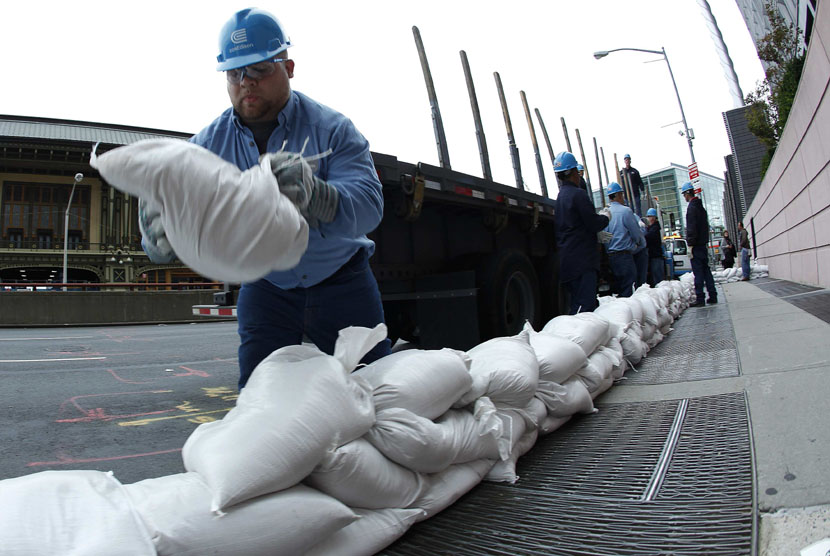 Seorang pekerja menumpuk karung pasir untuk menutupi kubah listrik di New York, Ahad (28/10). (Carlo Allegri/Reuters)