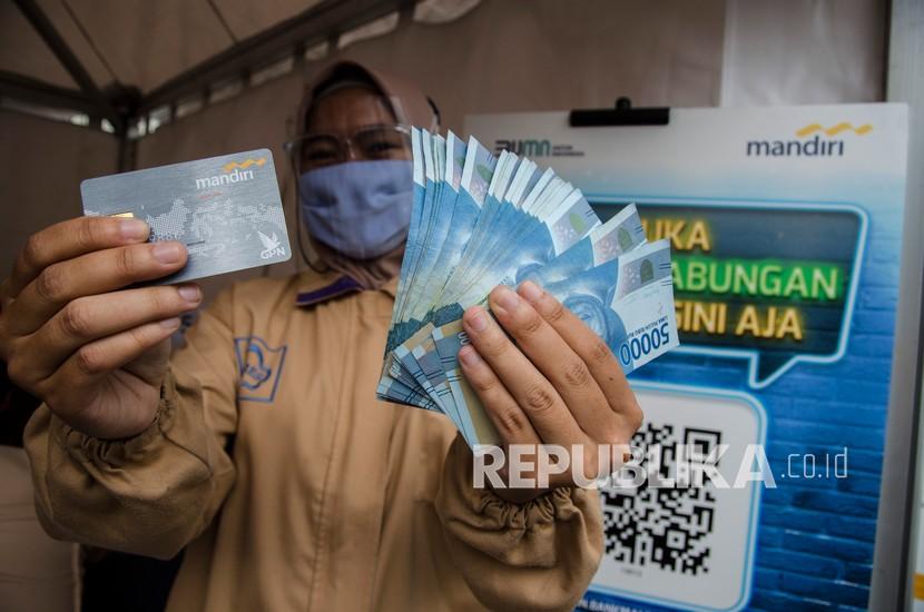 Seorang pekerja menunjukkan kartu ATM dan uang saat menerima Bantuan Subsidi Upah (BSU) (ilustrasi). BSU di Padang Panjang segera didistribusikan.