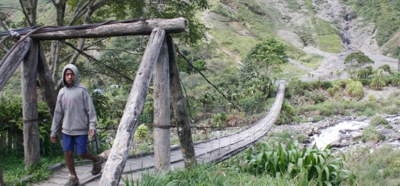 Seorang pelajar SMP tengah melintasi jembatan kayu di kaki bukit Yammo. Di sekitar jembatan ini kerap terjadi baku tembak antara aparat keamanan dan kelompok bersenjata.