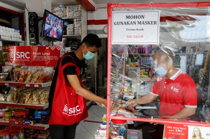 Seorang pelanggan melakukan pembayaran dari balik pembatas transparan di toko kelontong SRC Salim, Jakarta, pekan lalu. 