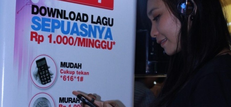 Seorang pelanggan Telkomsel sedang memanfaatkan ponselnya untuk mendengarkan lagu yang telah diunduh melalui LangitMusik HITS!.