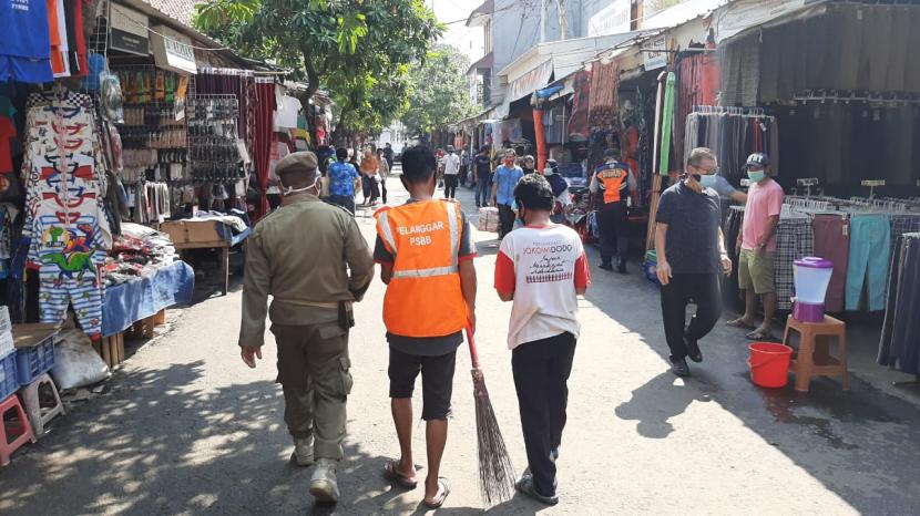 Seorang pelanggar protokol kesehatan pencegahan Covid-19 sedang menjalani sangsi membersihkan area Pasar Jatinegara, Jakarta Timur, Jumat (12/6). Musababnya, ia kedapatan tak menggunakan masker ketika memasuki area pasar. 