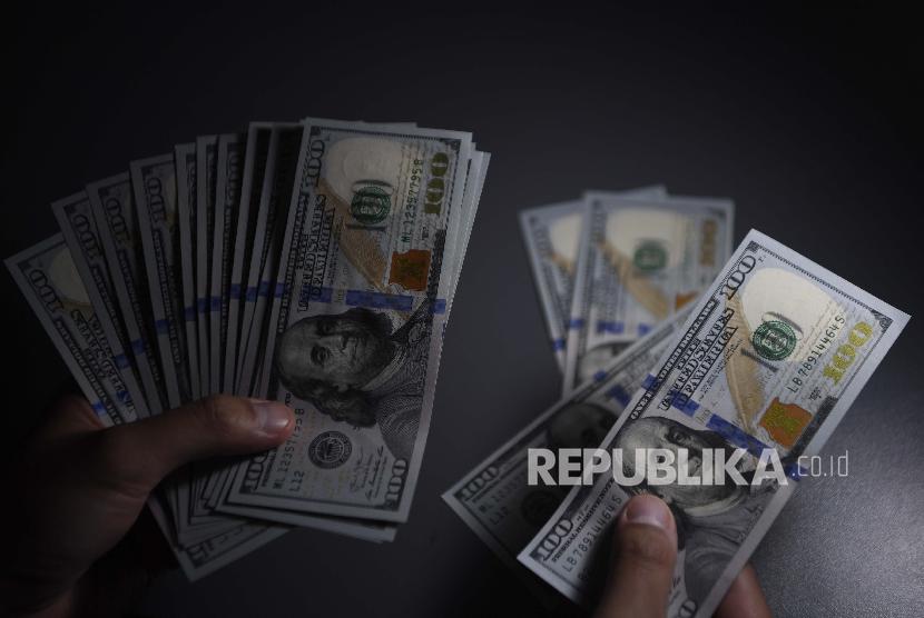 Seorang pembeli menghitung uang Dolar Amerika Serikat yang ditukarnya di gerai penukaran valuta asing, Jakarta, Senin.