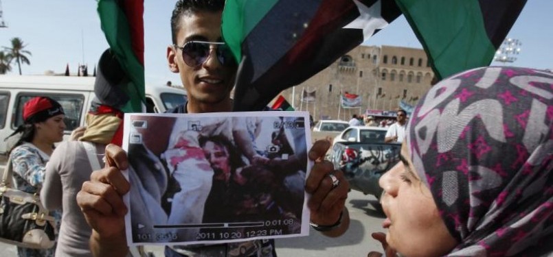 Seorang pemberontak memamerkan foto terbunuhnya Muammar Qaddafi. 