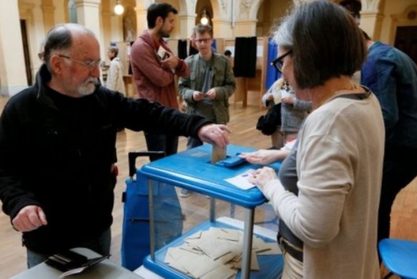 Seorang pemili Prancis memberikan suaranya dalam pemilu presiden putaran kedua di Lyon, Prancis, Ahad (7/5).