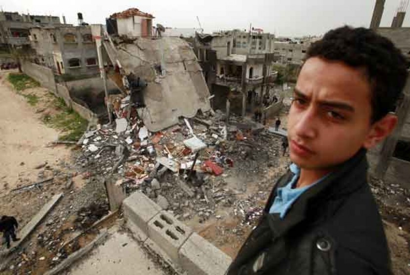  Seorang pemuda Palestina menatap gedung yang runtuh akibat serangan udara Israel di kawasan pemukiman sipil Jabalya, Gaza, Palestina. 