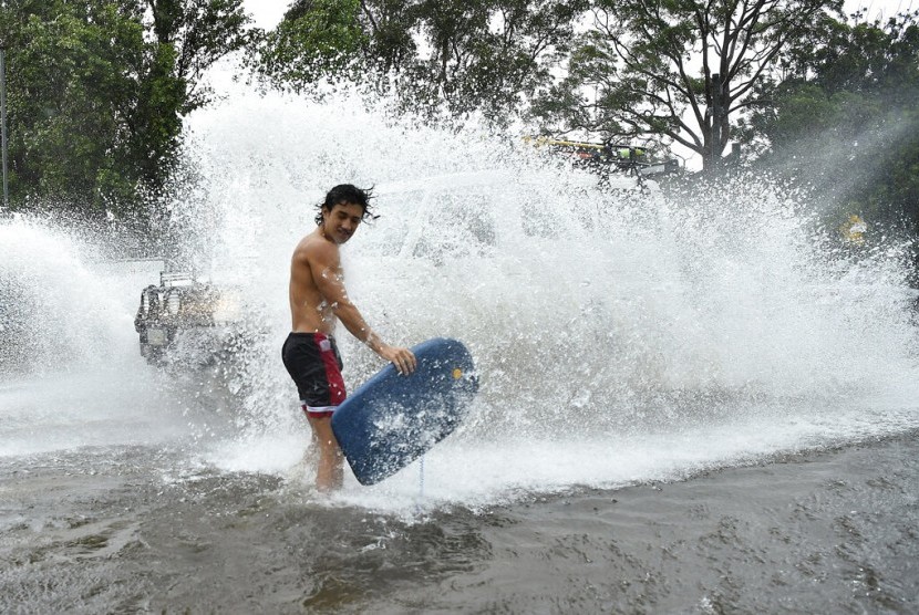  Seorang pemuda terciprat air dari mobil yang melintas banjir di Sydney, Australia, Ahad (9/2). Australia mengalami cuaca ekstrem beberapa pekan terakhir.