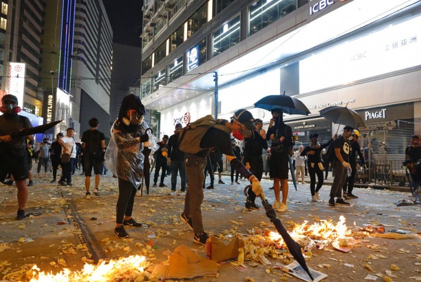 Seorang pendemo membakar foto Presiden China Xi Jinping dalam protes di Hong Kong, Selasa (1/10). Polisi menembak seorang pendemo di dada dari jarak dekat hingga berdarah di bahu.