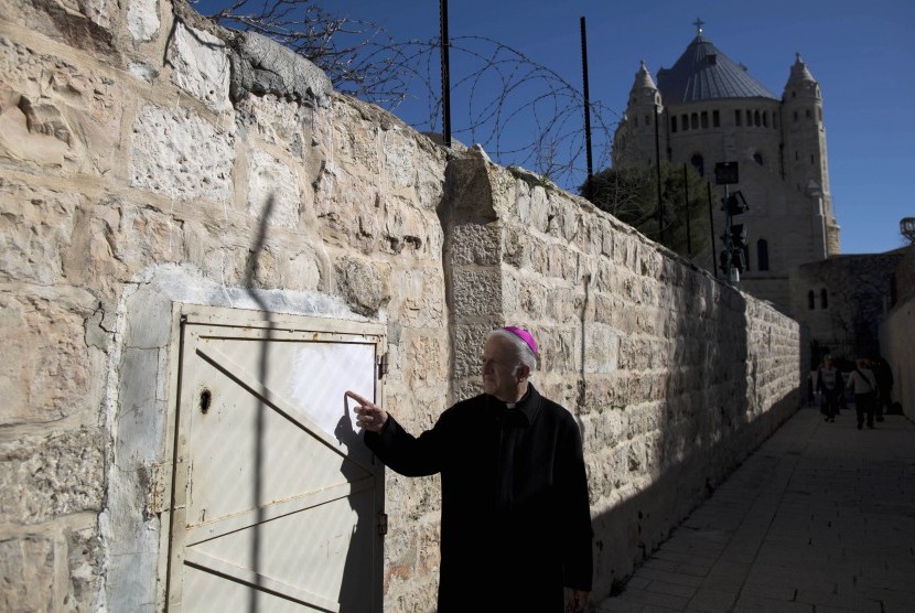 Seorang pendeta menunjukkan bekas graffiti anti-kristen di Dormition Abbey, Kota Tua, Jerusalem, Ahad (17/1). 