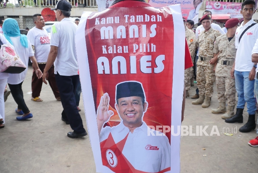 Seorang pendkung pasangan calon gubernur DKI Anies Sandi melintras di pada acara kampanye akbar di Jakarta, Ahad (5/2).