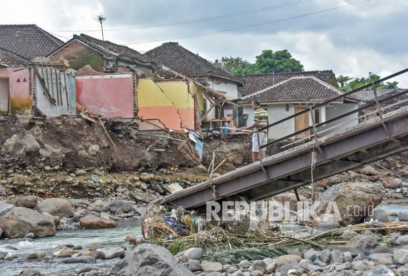 Seorang penduduk berdiri di atas jembatan yang ambruk diterjang banjir di Desa Lembah Sari, Kecamatan Batulayar, Lombok Barat, NTB, Kamis (9/12/2021). Empat hari pascabanjir bandang yang melanda daerah tersebut warga mulai kembali kerumahnya untuk membersihkan dan mengamankan barang-barangnya yang masih tersisa.