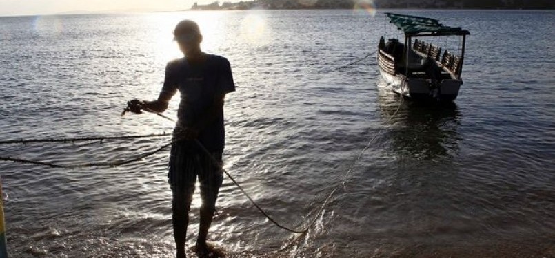 Seorang penduduk Lamu, Kenya, menarik perahu ke tepian pantai.