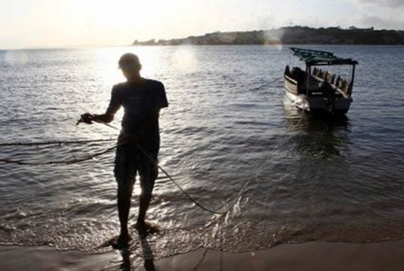 Seorang penduduk Lamu, Kenya, menarik perahu ke tepian pantai.
