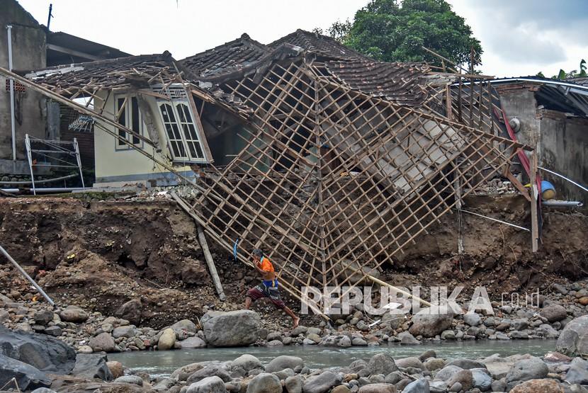 Seorang penduduk melintas dekat rumah yang ambruk akibat diterjang banjir di Desa Lembah Sari, Kecamatan Batulayar, Lombok Barat, NTB, Kamis (9/12/2021). (Ilustrasi)
