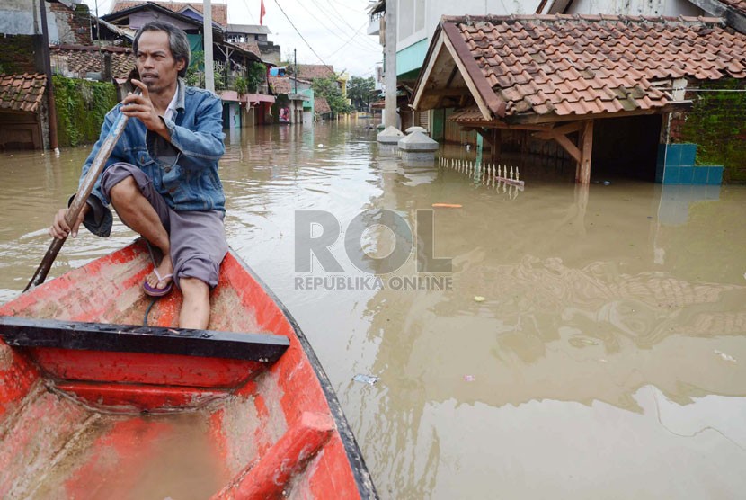    Seorang penduduk menyusuri perkampungan yang sudah terendam banjir di Cieunteung, Kecamatan Baleendah, Kabupaten Bandung, Ahad (15/12).  (Republika/Edi Yusuf)