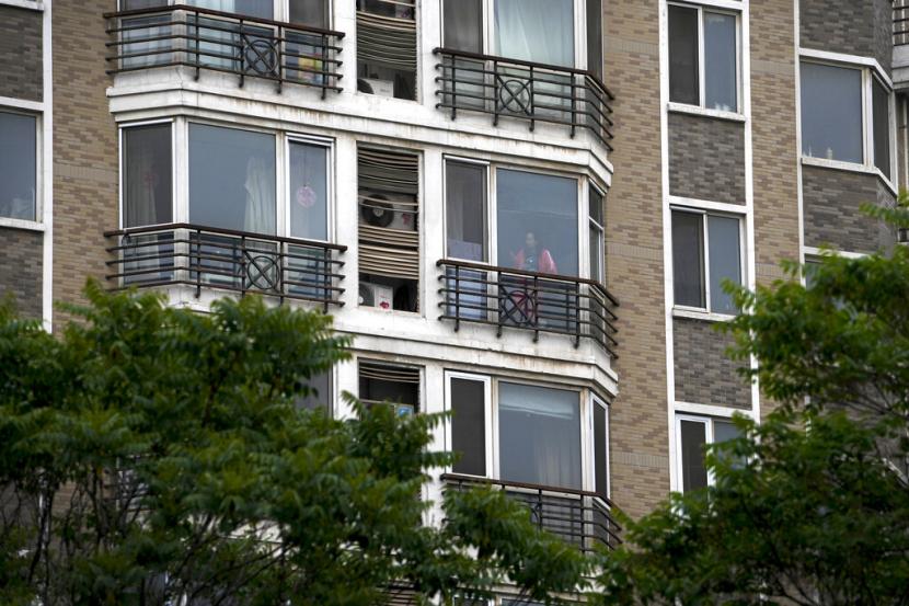 Seorang penduduk yang terkunci melihat-lihat ponsel di sebelah jendela apartemennya di distrik Chaoyang pada Selasa, 10 Mei 2022, di Beijing. Beijing, ibu kota, memulai putaran tiga hari pengujian massal untuk jutaan penduduknya Selasa dalam upaya untuk mencegah wabah berkembang ke proporsi Shanghai.