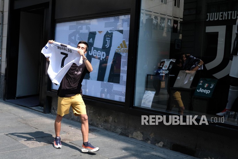 Seorang pendukung Juventus menunjukkan kaos Cristiano Ronaldo di luar toko Juve di via Garibaldi, Turin (11/7).