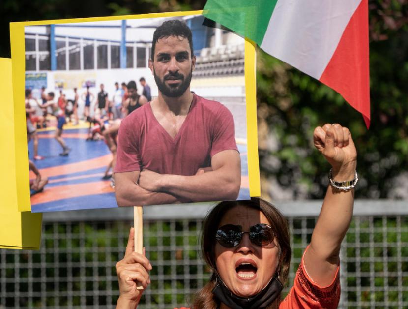  Seorang pendukung National Council of Resistance Iran (NWRI) dan Iranian Exile Society di Berlin, Jerman memegang poster bergambar pegulat Iran Navid Afkari, saat memprotes eksekusinya di kedutaan Iran di Berlin, Jerman, 12 September 2020.