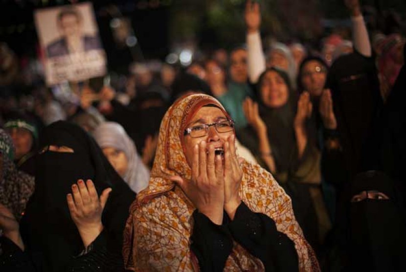  Seorang pendukung Presiden Mursi menangis saat protes menolak kudeta militer di Nasr City, Kairo, Senin (29/7).