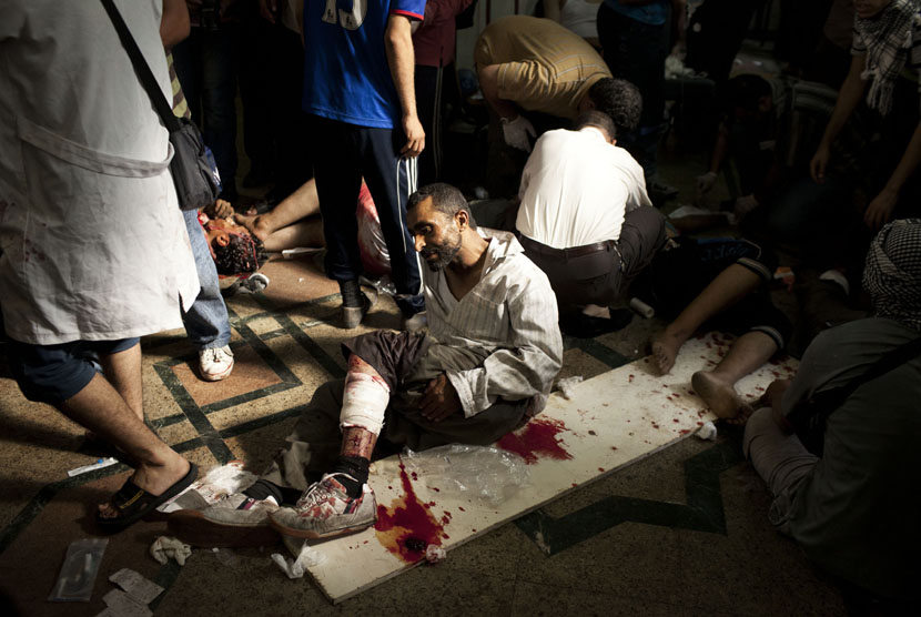  Seorang pendukung Presiden Mursi yang terluka tergeletak di lantai sebuah rumah sakit lapangan di Nasr City, Kairo, Sabtu (27/7). (AP/Manu Brabo)   
