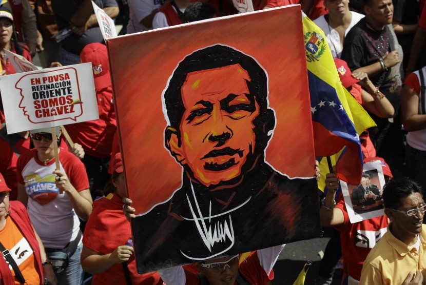   Seorang pendukung Presiden Venezuela Hugo Chavez mengangkat sebuah lukisan dirinya saat pelantikan secara simbolis Presiden Venezuela Hugo Chavez diluar Istana Presiden Miraflores di Caracas,Venezuela,Kamis (10/1).   (AP/Fernando Llano)