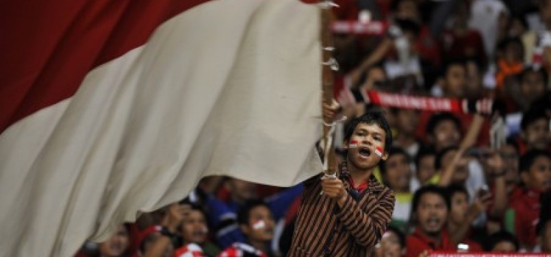 Seorang pendukung tim nasional Indonesia mengibarkan bendera merah putih dalam laga leg kedua kualifikasi Piala Dunia 2014 Zona Asia antara Indonesia vs Turkmenistan di Stadion Gelora Bung Karno, Senayan, Jakarta, beberapa waktu lalu.