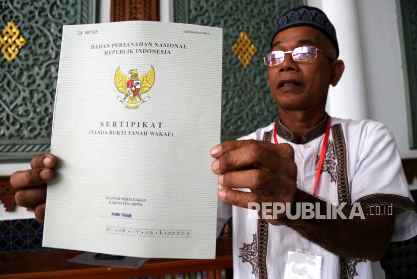 Seorang penerima memperlihatkan sertifikat tanah wakaf masjid, mushola, dan pasantren yang diserahkan Presiden Joko Widodo seusai melaksanakan ibadah Jumat di Banda Aceh, Aceh, Jumat (14/12/2018).
