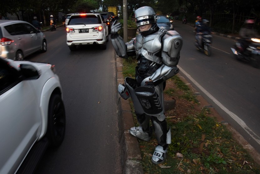 Seorang pengamen mengenakan kostum Robocop saat mengamen di kawasan Jalan Juanda, Depok, Jawa Barat, Kamis (30/3). 