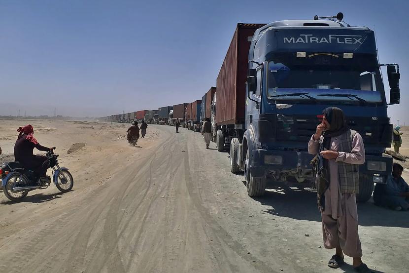 Seorang pengemudi berdiri di samping truk pengantar yang menuju Afghanistan menunggu untuk bergerak menuju sisi Afghanistan di titik penyeberangan perbatasan, di Chaman, Pakistan, Sabtu, 21 Agustus 2021. 