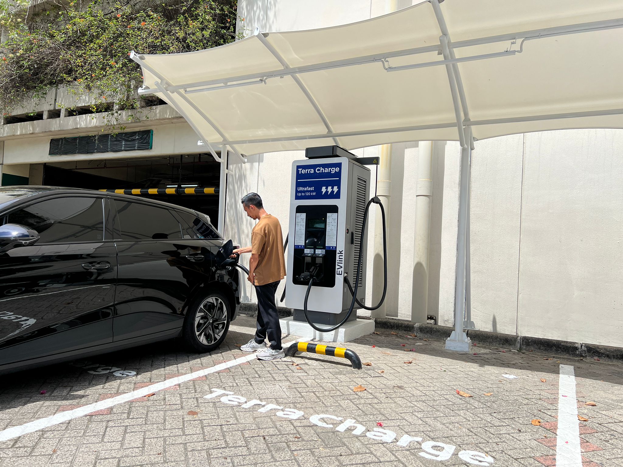 Seorang pengemudi melakukan pengisian daya mobil listril melalui SPKLU Terra Charge.
