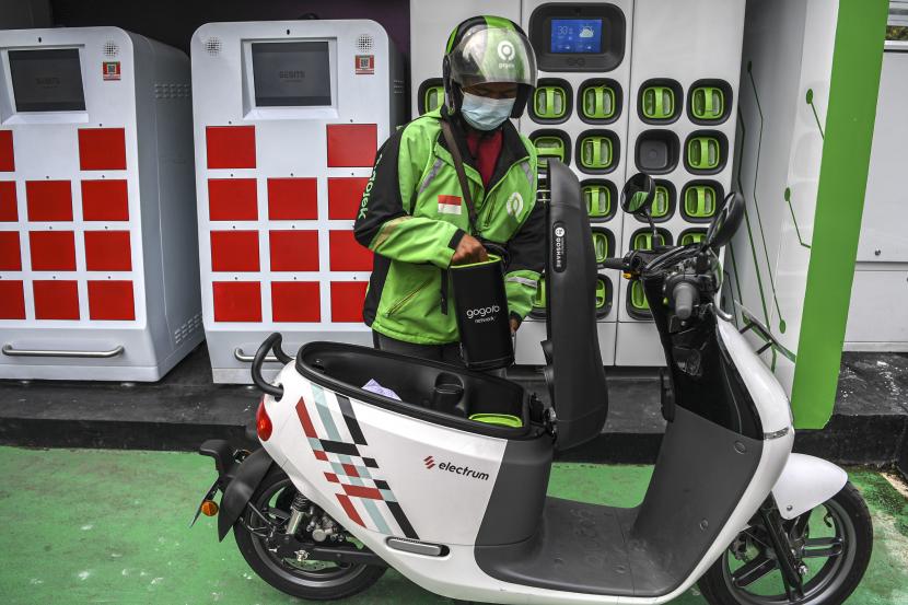 Seorang pengemudi ojek daring mengganti baterai sepeda motor listrik dengan yang sudah penuh terisi di Stasiun Penukaran Baterai Kendaraan Listrik Umum (SPBKLU) di SPBU Pertamina, Jalan MT Haryono, Jakarta. (ilustrasi).