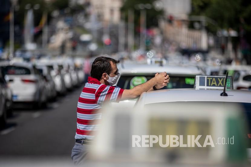 Seorang pengemudi taksi yang mengenakan masker untuk mencegah penyebaran coronavirus saat protes terhadap supir taksi di pusat kota Madrid, Spanyol, Selasa, 30 Juni 2020. Sopir taksi meminta bantuan karena kurangnya klien dan persewaan pribadi. 