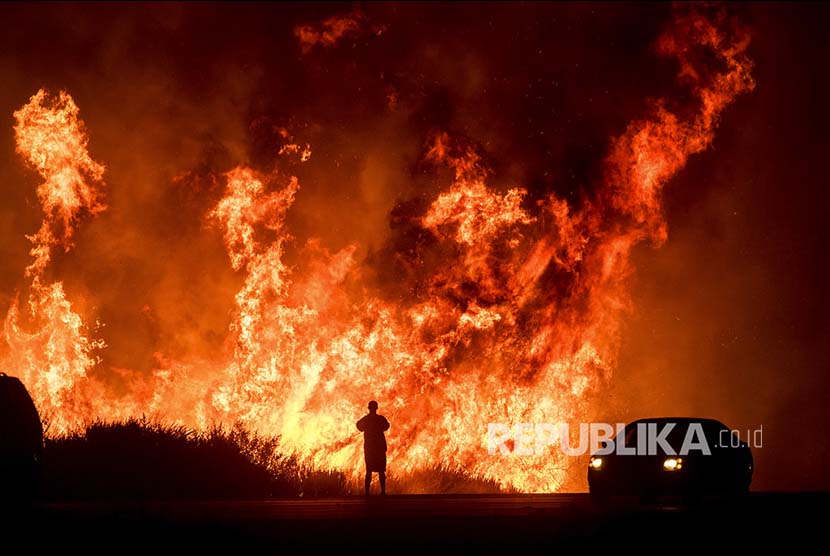 Seorang pengendara di Jalan Tol  Highway 101 menonton 'Thomas Fire' (kebakaran yang melanda California) 'menyeberangi' jalan  Ventura, California, Amerika Serikat.