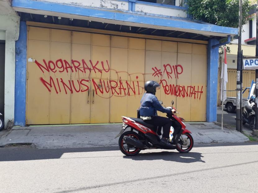 Seorang pengendara melintasi Jalan Kusumoyudan, kampung Pringgading, Solo, Jawa Tengah, Selasa (24/8). Di ruas jalan tersebut ditemukan tulisan vandalisme yang mengkritik pemerintah.