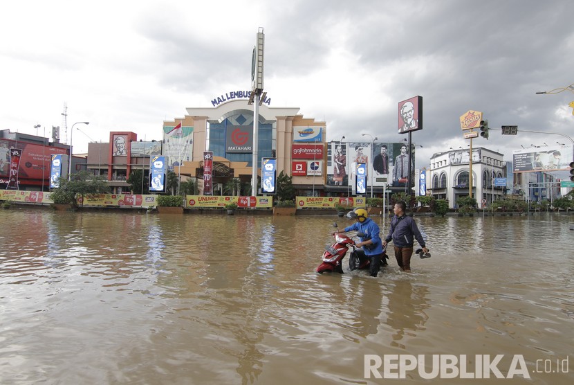 Seorang pengendara mendorong motornya Yang mogok akibat melintas di banjir yang terjadi di kawasan Simpang Lembuswana, Samarinda, Kalimantan Timur, Senin (10/6/2019).