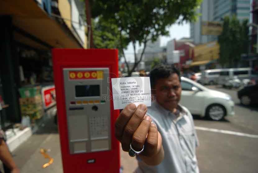 Seorang pengendara roda empat memasukan koin di parkir meter di Jalan Sabang, Jakarta Pusat, Jumat (26/9). (Republika/Raisan Al Farisi).