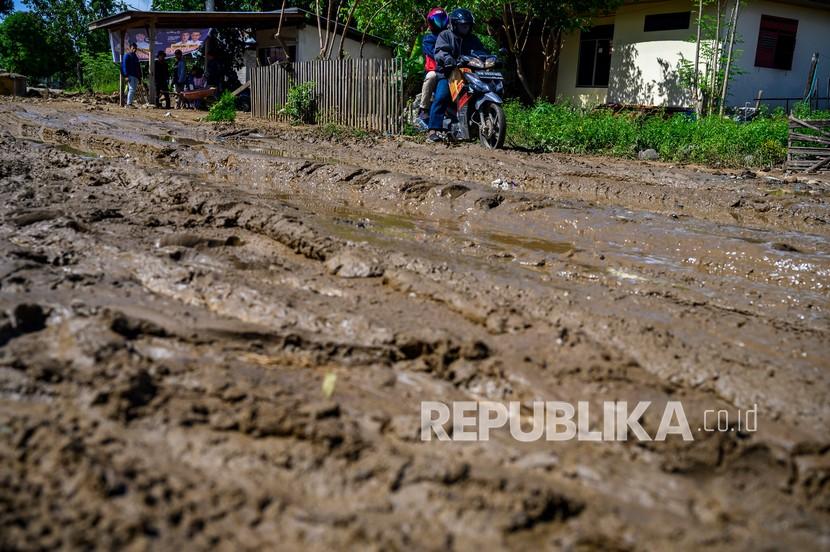 Seorang pengendara sepeda motor melintasi jalan yang dipenuhi lumpur di jalur Transsulawesi.