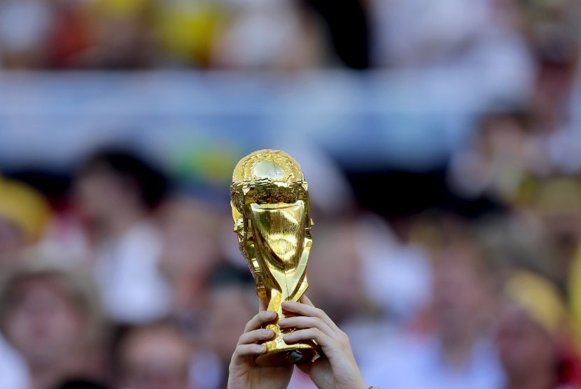 Seorang penggemar mengangkat trofi replika Piala Dunia