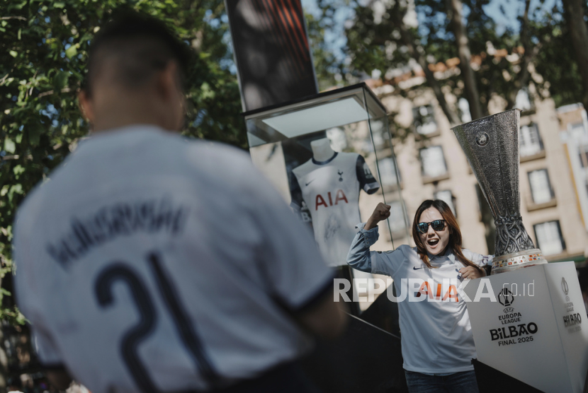 Seorang penggemar Tottenham berpose di samping trofi Liga Europa di zona penggemar sebelum pertandingan final sepak bola Liga Europa UEFA antara Manchester United dan Tottenham Hotspur di Stadion San Mamés Bilbao, Spanyol, Selasa (20/5/2025).