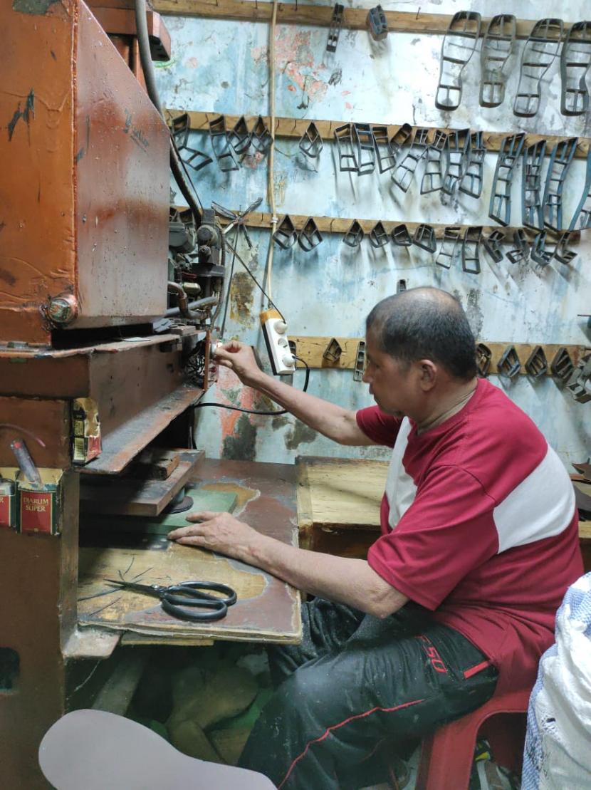 Seorang pengrajin sepatu sedang mengerjakan salah satu karyanya.