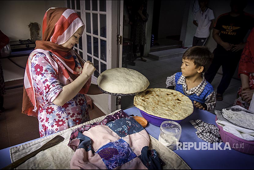 Seorang pengungsi anak memperhatikan ibu yang membuat Naan, kue khas Afghanistan, di rumah komunitas untuk pengungsi dan pencari anak di Kota Pekanbaru.
