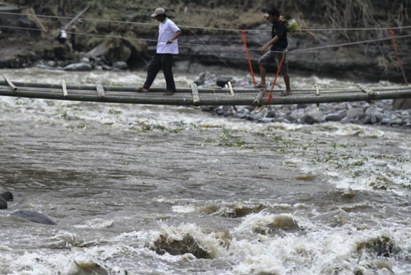 Seorang pengungsi melintasi jembatan darurat yang dibangun di dusun Klangon, Pandansari, Ngantang, Malang, Jawa Timur, Sabtu (22/2). Jembatan tersebut dibangun sementara untuk menggantikan jembatan utama penghubung dusun Klangon dengan akses jalan utama ya