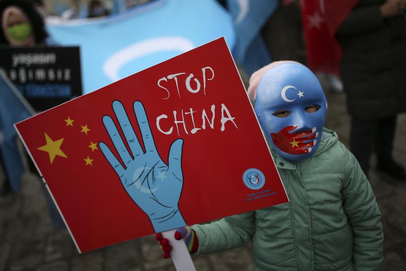 Seorang pengunjuk rasa dari komunitas Uighur yang tinggal di Turki, memegang plakat anti-China selama protes di Istanbul, ilustrasi