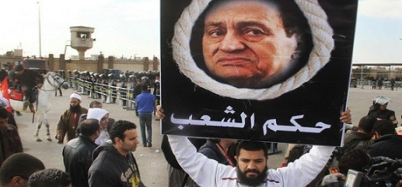 Seorang pengunjuk rasa, keluarga korban yang tewas dalam Revolusi Mesir, membentangkan poster bergambar mantan Presiden Hosni Mubarak dengan latar belakang tali gantungan bertuliskan hukum rakyat, Senin (2/1).