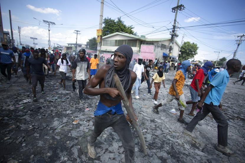 Seorang pengunjuk rasa membawa sepotong kayu yang menirukan senjata selama protes menuntut pengunduran diri Perdana Menteri Ariel Henry. Pemerintah Taiwan membantu Haiti membeli rompi anti-peluru dan peralatan protektif personel lainnya