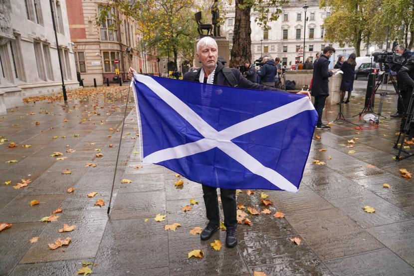Seorang pengunjuk rasa memegang bendera Skotlandia di luar Mahkamah Agung di London, Rabu, 23 November 2022. Mahkamah Agung Inggris pada Rabu memutuskan bahwa Skotlandia tidak memiliki kekuatan untuk mengadakan referendum baru tentang kemerdekaan tanpa persetujuan dari pemerintah Inggris. Putusan tersebut merupakan kemunduran bagi kampanye pemerintah Skotlandia untuk melepaskan diri dari Inggris.
